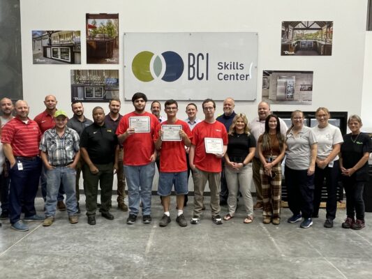 A group photo of three men with disabilities holding BCI Skills Center graduation certificates with leaders from BCI and True Manufacturing